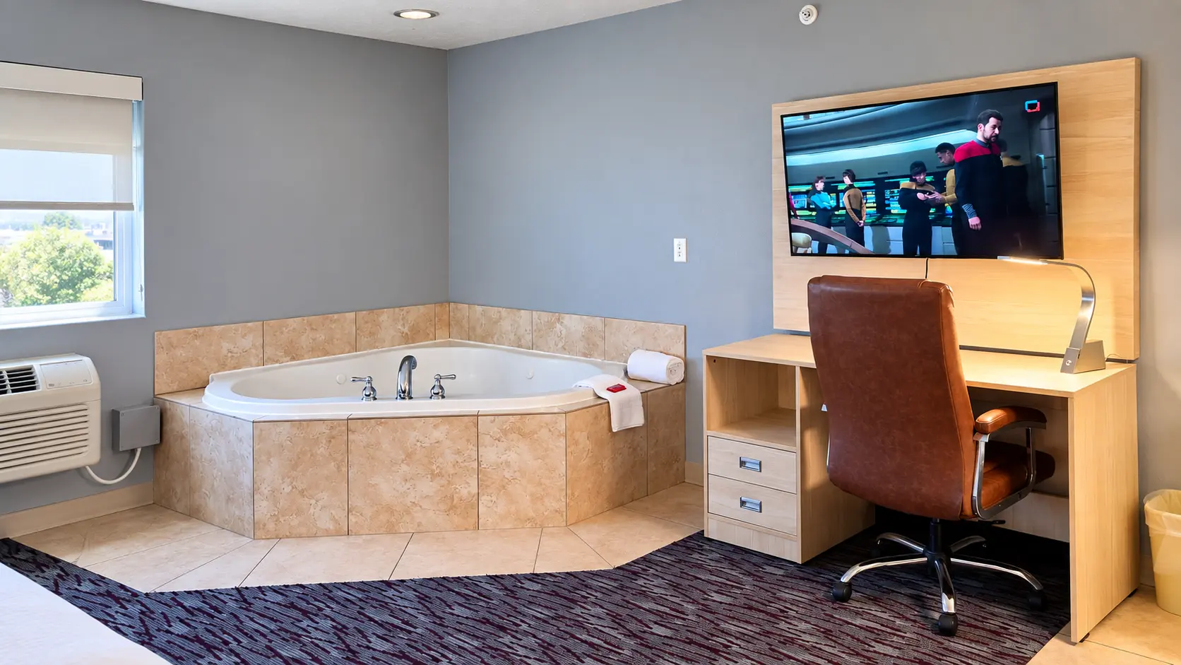 Corner jacuzzi in a tiled surround beside a desk and wall-mounted TV — Best Western Vernal Inn, Vernal Utah