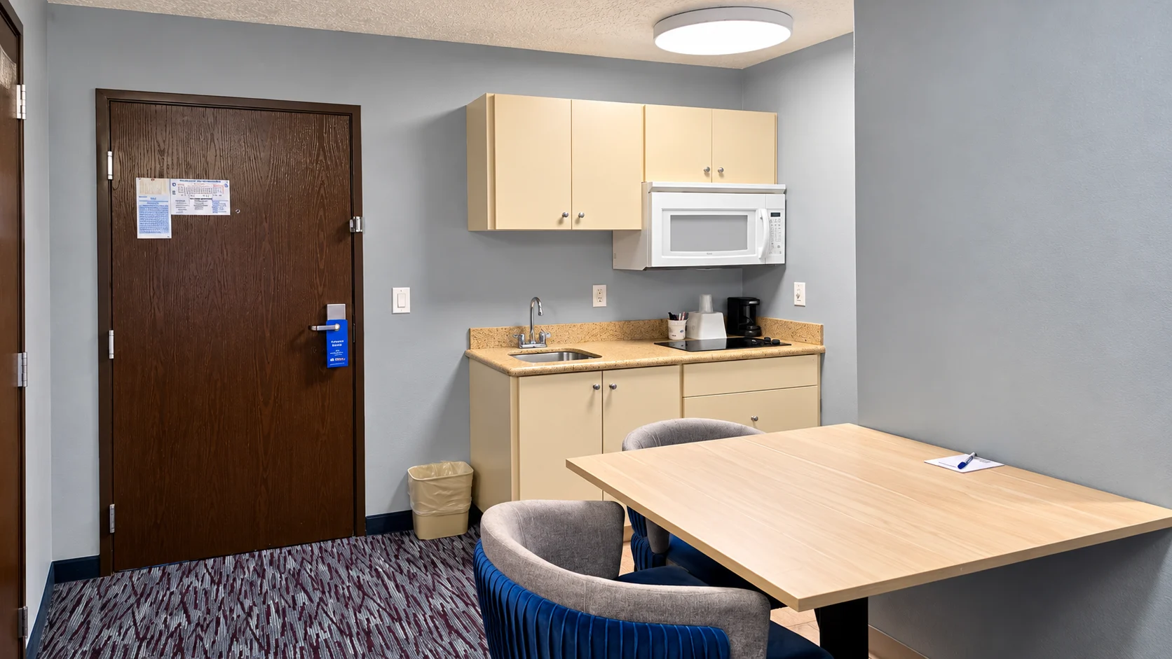 Kitchenette with microwave and coffee maker beside a dining table and entry door — Best Western Vernal Inn, Vernal Utah